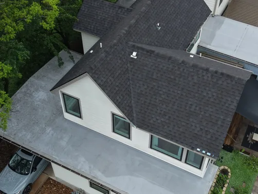 Front eave and dark shingle roof from Zilker Roofing’s wind-damage repair project
